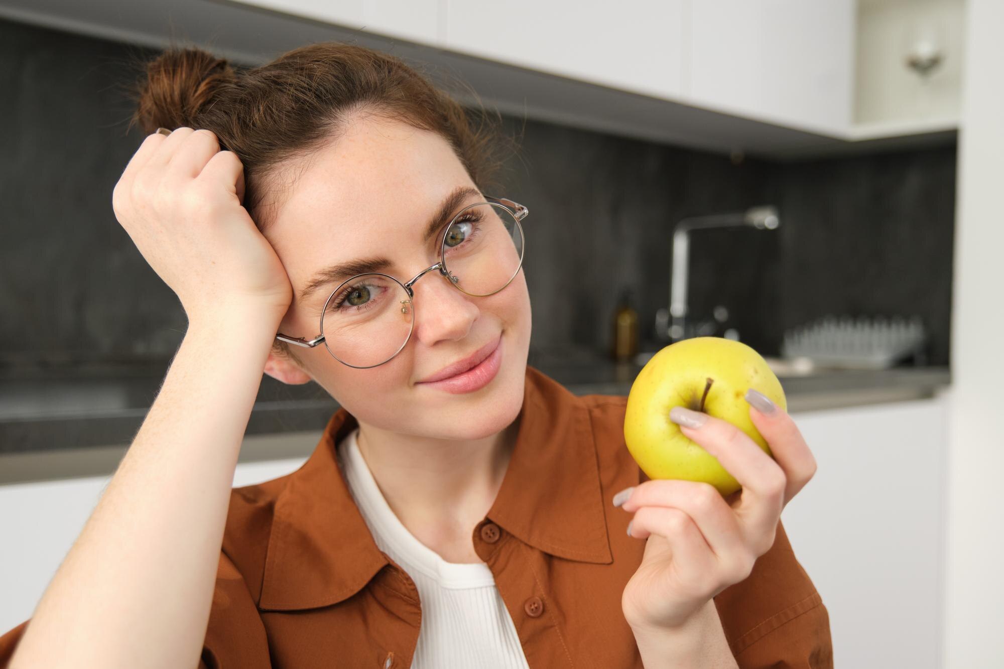 Persona sosteniendo suplementos para el cuidado de la visión frente a una ventana iluminada